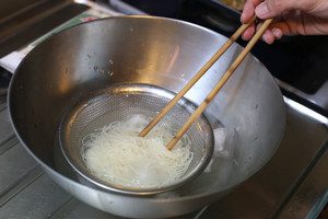 茹であがった麺をすばやくザルに移し、水で粗熱を取った後、氷水で冷やす