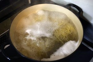 大きめの鍋に水、塩を入れ火をつけ、沸騰したらパスタを茹で始める。